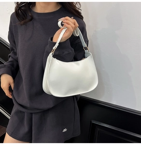 Detail view of white glossy hobo bag with golden D-ring hardware on model