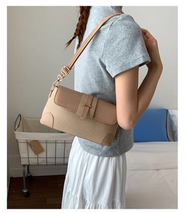 Detail of linen baguette bag with adjustable leather strap worn by a model