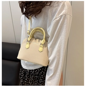 Detail view of woven shell bag featuring pale yellow leather straps and fashion lettering