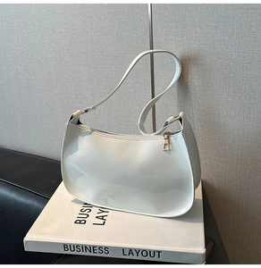 Detail of white patent leather hobo bag with gold zipper and minimalist crescent shape