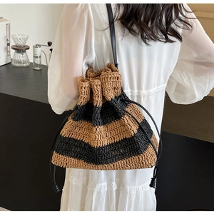 Detail of striped woven bucket bag with black leather drawstring on white dress