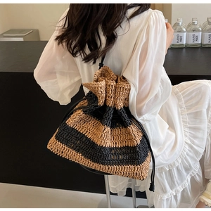 Detail of striped straw bucket bag with drawstring closure and vintage woven texture