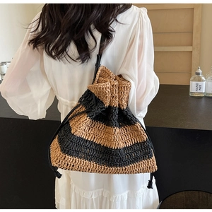 Detail of handwoven striped bucket bag with drawstring closure and leather shoulder strap