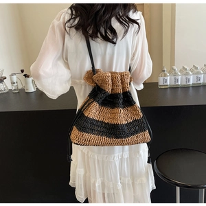 Detail of striped woven shoulder bag with drawstring closure and slim black strap