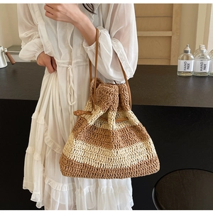 Detail of striped straw bucket bag showing woven texture and brown leather drawstring strap