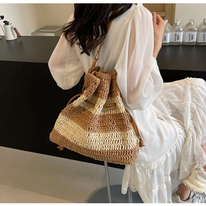 Detail of striped straw bucket bag featuring leather drawstring and woven texture
