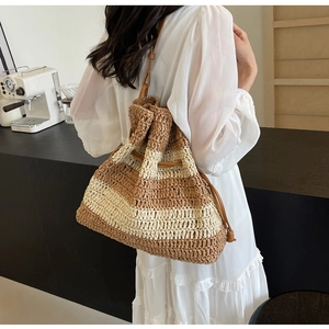 Detail of striped straw bucket bag with brown leather drawstring and shoulder strap