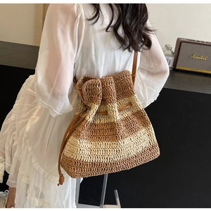 Detail of striped straw bucket bag featuring a large decorative bow and leather drawstring