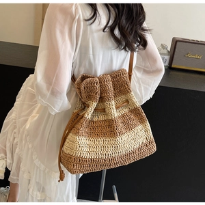 Macro detail of striped straw bucket bag with leather drawstring and shoulder strap