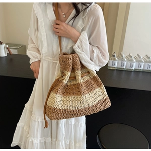 Detail of striped straw bucket bag with drawstring closure and leather shoulder strap