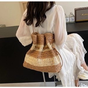 Detailed close-up of handmade woven straw bucket bag with striped pattern and leather straps