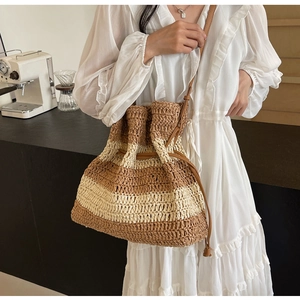 Detail of handwoven striped straw bucket bag with leather drawstring and shoulder strap