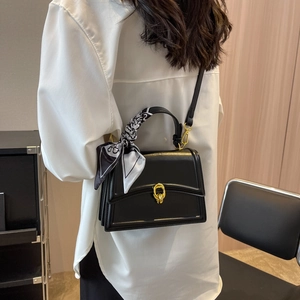 Elegant black square leather handbag with gold buckle and scarf detail on white shirt