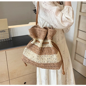 Detail of striped straw bucket bag with leather strap worn by model in a boho chic setting