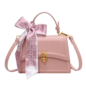 Pink square handbag with gold ring clasp and decorative bear scarf on handle