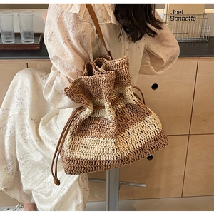 Detail of striped straw bucket bag featuring drawstring closure and leather strap