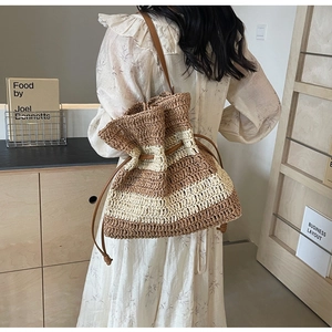 Detail of striped straw bucket bag with leather strap and drawstring closure for summer