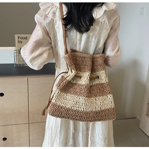 Detail of the woven straw bucket bag showing brown stripes and leather drawstring closure