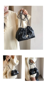 Close-up of black woven leather texture with silver chain strap and pearl shell charms
