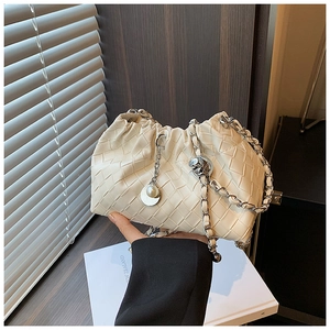 Detail of woven cream crossbody bag with silver chain and decorative pearl charm