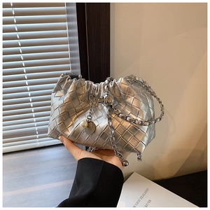 Close-up of metallic silver woven handbag with pearl pendant and metal chain detail