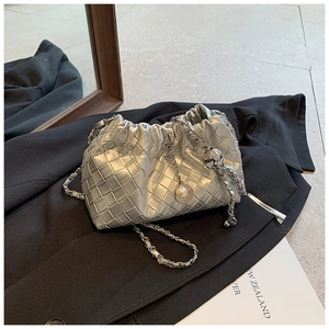 Detailed shot of silver woven shoulder bag with chain strap and pearl pendant