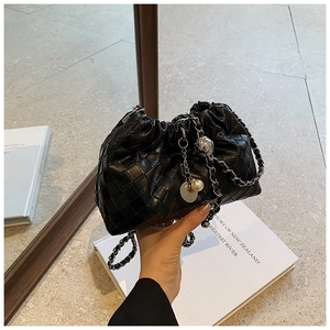 Detail of black woven leather handbag with silver chain and decorative pearl charm