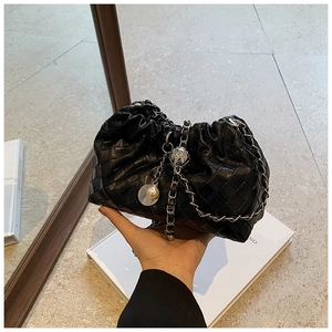 Detail of black woven leather cloud bag with silver chain and pearl charm detail