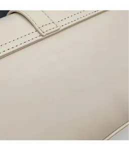 Close-up of beige leather shoulder bag with detailed fine stitching and matte texture