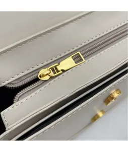 Detailed macro view of glossy gold metal zipper head and magnetic clasp on beige bag