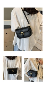 Detail of small black leather crossbody bag with iconic gold buckle in lifestyle setting