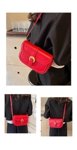 Detail view of red glossy leather saddle bag with gold horse-shoe buckle decoration