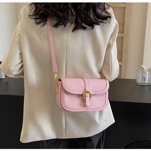 Detail of pink leather crossbody bag featuring a golden horseshoe metal buckle and strap