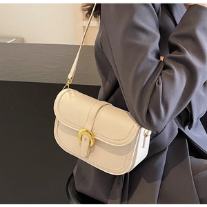 Detail of cream white leather saddle bag with gold horseshoe buckle on grey blazer