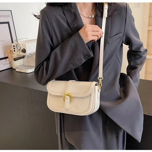 Detail of creamy white leather handbag featuring a golden horseshoe metallic buckle
