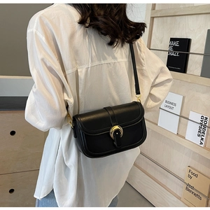 Close-up of a black leather saddle bag with a premium golden crescent metal buckle