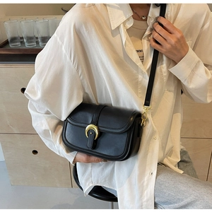 Detail of a chic black saddle bag with a round flap and signature golden moon metal buckle