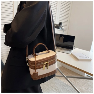 Minimalist cream and brown contrast box bag with gold zippers in a modern office setting