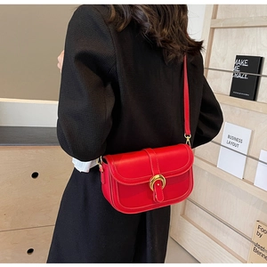 Detail of red leather saddle bag with golden horseshoe buckle on black blazer