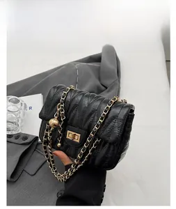 Detail of black quilted leather bag featuring a gold chain strap and metal swivel lock
