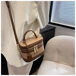 Detail of a vintage cylindrical crossbody bag in brown leather with a model in a suit