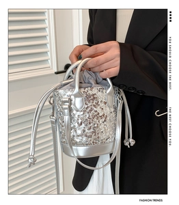 Detail view of silver sequin bucket bag with circular sequins and metal ring handle