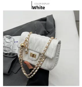 Close-up of white quilted crossbody bag with golden chain strap and V-stitch detail