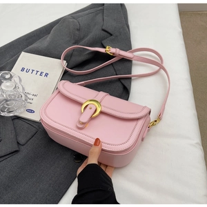 Detail of pink faux leather crossbody bag with a large golden ring buckle and flap
