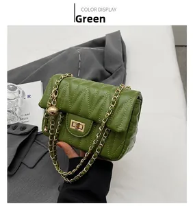 Detail of green quilted crossbody bag with golden twist lock and metal chain strap