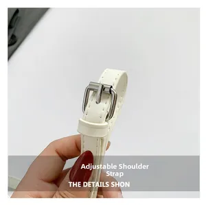 Detail of adjustable white PU leather shoulder strap with silver metal buckle on bucket bag