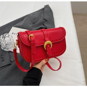 Detail of red leather square bag with gold horseshoe buckle and adjustable strap