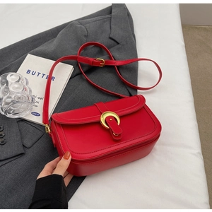 Close-up of red leather handbag featuring a stylish gold horseshoe metal buckle detail