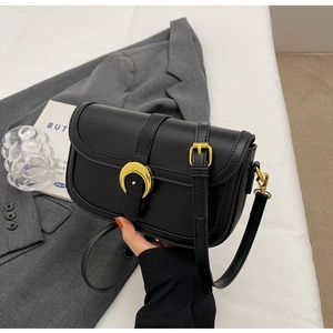 Detailed close-up of a black leather crossbody bag with a golden crescent metal buckle