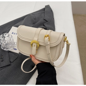 Detailed view of cream leather shoulder bag with elegant gold horseshoe buckle hardware